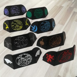 May include: Set of ten black and white game pieces with different designs, including a dragon, a castle, a wolf, and a tree. The pieces are made of wood and have a smooth finish.