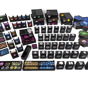 Puede incluir: Una colección de cajas y bandejas de almacenamiento negras, probablemente para un juego de mesa. Las cajas son de varios tamaños y formas, algunas con tapas, y contienen componentes del juego como cartas, fichas y dados. Los componentes presentan diseños y símbolos coloridos.