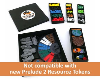 May include: A black box with the text "Tinkering Paws" and a cat paw print logo. The box is open and contains a game board with a circular area for tokens. The board is surrounded by compartments for storing game pieces. The compartments are filled with various colored plastic tokens. The text "Not compatible with new Prelude 2 Resource Tokens" is displayed below the image.
