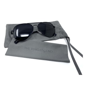 May include: Black aviator sunglasses with a gray fabric case. The case has the text "THE RING LEGEND" printed on it.