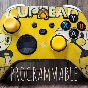 May include: A yellow Xbox controller with a Cuphead design. The controller has a black d-pad, black buttons, and yellow thumbsticks. The controller is labelled "PROGRAMMABLE".