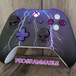 May include: Custom Xbox controller with a black and purple lightning bolt design. The controller features purple buttons and thumbsticks, a purple directional pad, and the word "PROGRAMMABLE" in a stylized font.