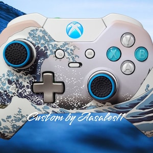 May include: Custom Xbox controller featuring a wave design in shades of blue, white, and beige. The controller has black thumbsticks with blue accents, and the face buttons are teal and gray. The Xbox logo is illuminated in blue. Text on the controller reads "Custom by Aasales11".