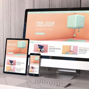 May include: A desktop computer, tablet and smartphone are displayed on a desk. The computer screen shows a website with the text "Find Your Creativity" and a 3D graphic of a light blue cube dripping with blue paint. The tablet and smartphone screens show similar designs with the same text.