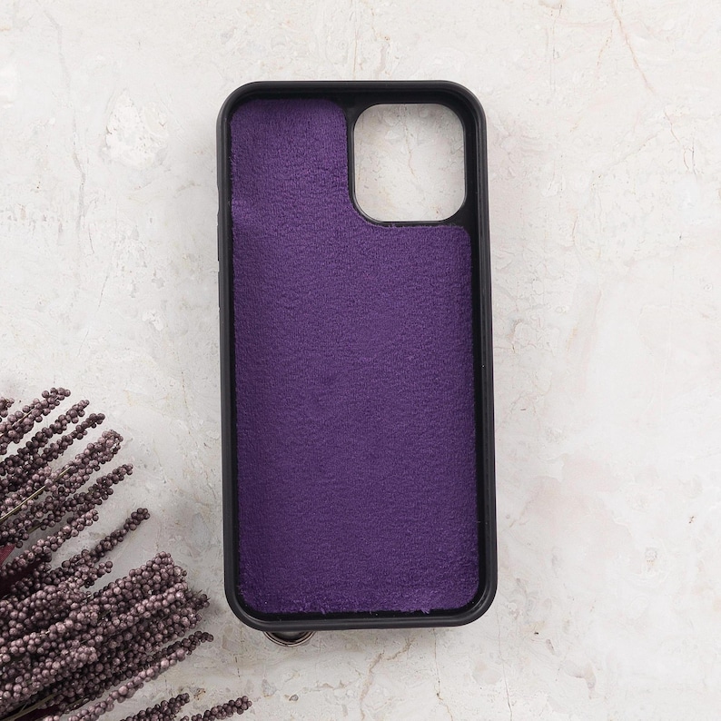 Puede incluir: Una funda de tel&eacute;fono rectangular con marco negro y un forro interior de tela texturizada de color morado intenso. La funda presenta un gran recorte cuadrado en la esquina superior derecha para el m&oacute;dulo de la c&aacute;mara y esquinas redondeadas.