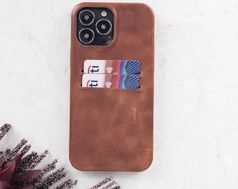 Peut inclure: Une coque de téléphone en cuir marron avec une découpe rectangulaire pour l'appareil photo en haut et deux fentes horizontales au dos. Chaque fente contient une carte bancaire avec un logo Citi et un motif graphique bleu, rouge et blanc.