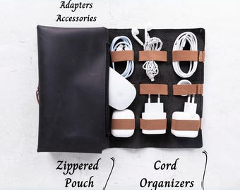 May include: Black leather zippered pouch with cord organizers. The pouch holds white charging cables, adapters, and a white mouse. Brown leather straps secure the cords and adapters. Text on the image reads "Adapters Accessories" and "Cord Organizers".