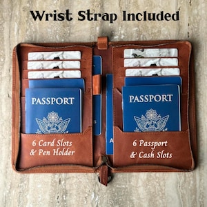 May include: A brown leather travel wallet with a zipper closure. The wallet has multiple compartments for cards, passports, and cash. The text "Wrist Strap Included", "6 Card Slots & Pen Holder", and "6 Passport & Cash Slots" are visible.