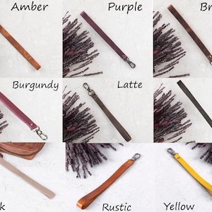 May include: A collection of leather wrist straps in various colors, including amber, purple, brown, burgundy, latte, black, mink, rustic, and yellow. Each strap has a metal clasp for attachment. The straps are displayed on a light-colored surface.