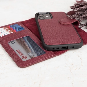 May include: A burgundy textured wallet phone case with a magnetic closure, featuring an integrated smartphone holder, multiple card slots, and a clear ID window. The interior is lined with a soft burgundy material, and the exterior has a pebbled finish.