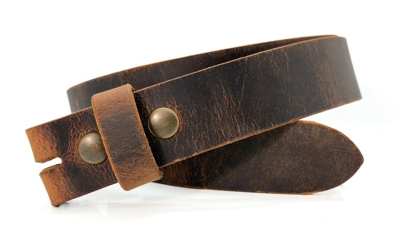 May include: A dark brown leather belt featuring a distressed, textured finish and a pointed tip. The belt is secured with two round, antique brass-colored metal rivets that hold the leather loop in place against the main strap.