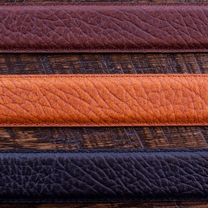 Pode incluir: Tr&ecirc;s tiras horizontais de material texturizado em castanho escuro, castanho alaranjado m&eacute;dio e preto. Cada tira apresenta um padr&atilde;o de gr&atilde;o distinto e &eacute; rematada com costuras retas e tonais ao longo das margens superior e inferior.