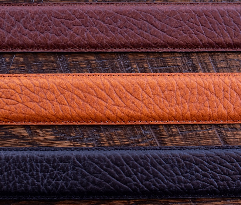 Pode incluir: Tr&ecirc;s tiras horizontais de material texturizado em castanho escuro, castanho alaranjado m&eacute;dio e preto. Cada tira apresenta um padr&atilde;o de gr&atilde;o distinto e &eacute; rematada com costuras retas e tonais ao longo das margens superior e inferior.