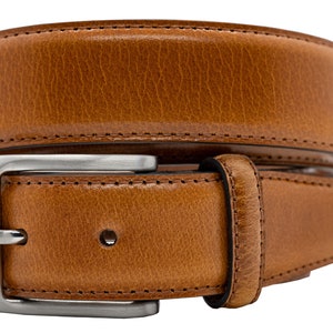 May include: A tan leather belt with a textured surface and visible stitching along the edges. The belt features a rectangular silver-toned metal buckle with a single prong and a matching leather keeper loop, coiled into a circular shape.