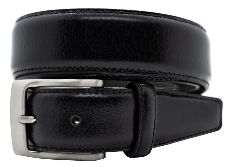 May include: A black leather belt featuring a smooth, polished finish and a rectangular silver-toned metal buckle. The belt strap has visible stitching along the edges and a single belt loop near the buckle, coiled into a circular shape.