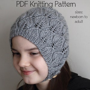 May include: A gray knitted hat with a lacy pattern. The hat has a flap that can be pulled down to cover the ears. The hat is suitable for newborns to adults.  PDF Knitting Pattern.