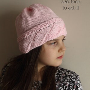 May include: A pink knitted hat with a cable pattern. The hat is worn by a person with long brown hair. The text "PDF Knitting Pattern" and "size: teen to adult" is visible in the image.