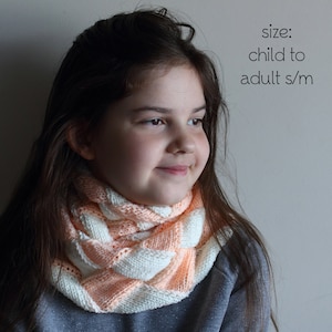Puede incluir: Un patrón de tejido PDF para un cuello, con el texto "size: child to adult s/m". El cuello está tejido en un patrón de tejido de cesta con rayas alternas de hilo melocotón y blanco. El cuello está alrededor del cuello de una persona.
