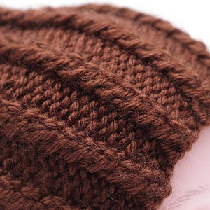 K&ouml;nnte beinhalten: Eine braune Strickm&uuml;tze mit Zopfmuster.