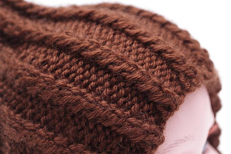 K&ouml;nnte beinhalten: Eine braune Strickm&uuml;tze mit Zopfmuster.