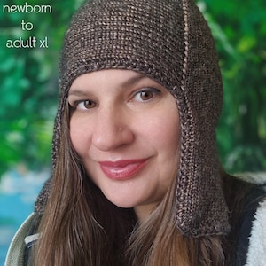 Peut inclure: Une personne porte un bonnet marron tricoté avec des cache-oreilles. Le chapeau est fait d'un fil texturé et comporte une bande marron clair au centre. Le texte sur l'image indique "PDF Knitting Pattern" et "sizes: newborn to adult xl."