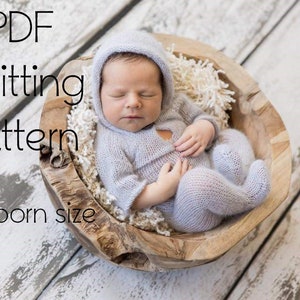 Può includere: Modello di maglia PDF per un completo per neonato. Il completo è una tutina con cappuccio in maglia blu chiaro. Il bambino sta dormendo in una ciotola di legno.