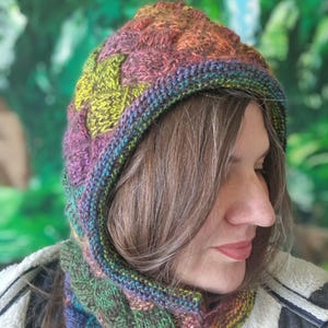 May include: A knitted hood and cowl set in a variety of colors, including green, purple, and orange. The text "PDF Knitting Pattern" is displayed at the top. The hood and cowl are made with a textured stitch pattern.