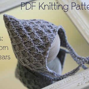 May include: A gray knitted baby hat with a pointed hood and ties. The hat is displayed on a white surface with a mirror reflection. The text "PDF Knitting Pattern" and "sizes: newborn to 6 years" is visible in the image.