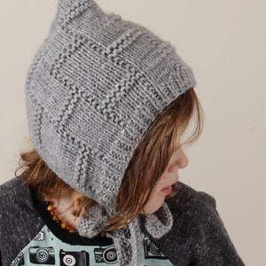 Peut inclure: Un bonnet gris en tricot avec un sommet pointu et une longue cravate. Le bonnet est port&eacute; par un enfant aux cheveux bruns et une chemise &agrave; imprim&eacute; cam&eacute;ra.