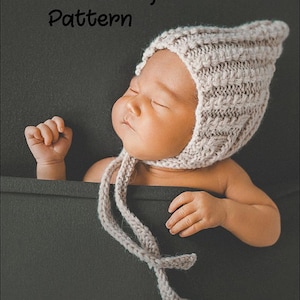 May include: A PDF knitting pattern for a baby bonnet. The bonnet is a light beige colour and has a simple stitch pattern. The bonnet is tied with a long, thin string.