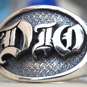 Puede incluir: Un anillo de plata con la palabra "DIGO" en fuente gótica.