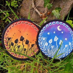 May include: Two round embroidered patches with a mushroom theme. One patch features a sunset with orange, red, and yellow colors and black mushrooms. The other patch features a night sky with blue, purple, and white colors and white mushrooms.