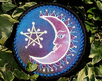 May include: A round, embroidered patch with a crescent moon and a five-pointed star. The moon is pink and purple with a face, and the star is yellow. The background is a gradient of blue and purple.