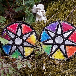 May include: Two circular rainbow-colored embroidered patches with a silver star in the center. The patches are surrounded by a black border and have a decorative silver trim.