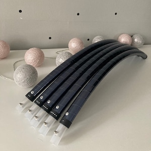 May include: Five black hoop dance hoops stacked on top of each other. The hoops are made of a flexible material and have a textured surface. The hoops are decorated with silver accents.
