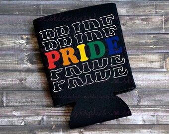 May include: Black drinks cooler featuring the word "PRIDE" in rainbow colours, with the word "PRIDE" repeated in white. Set against a wooden background.