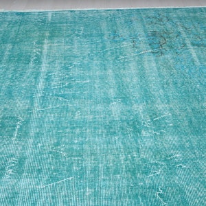 May include: A teal blue rug with a faded, distressed pattern. The rug has a woven texture and a subtle, faded design.