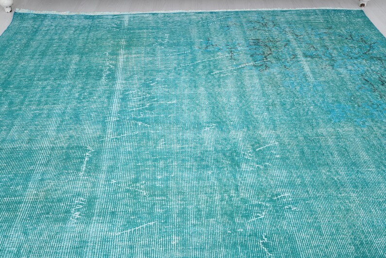 May include: A teal blue rug with a faded, distressed pattern. The rug has a woven texture and a subtle, faded design.