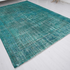 May include: A teal blue vintage rug with a faded pattern. The rug has a distressed look and is made of a soft, woven material.