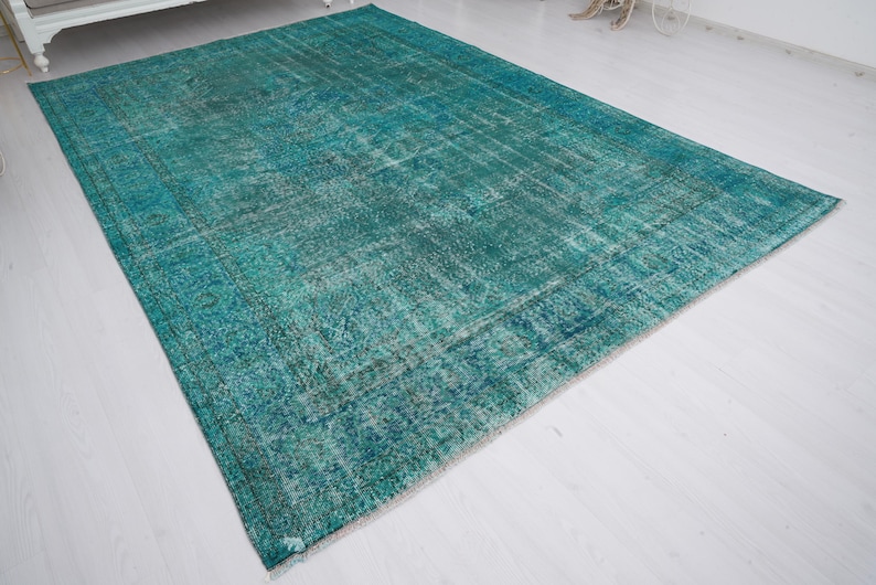 May include: A teal blue vintage rug with a faded pattern. The rug has a distressed look and is made of a soft, woven material.