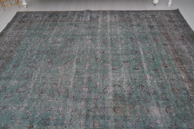 May include: A vintage teal and gray rug with a faded floral pattern. The rug has a distressed look and is made of a soft, woven material.