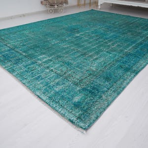 May include: A teal blue vintage rug with a distressed, faded look. The rug has a subtle pattern and is made of a soft, woven material.