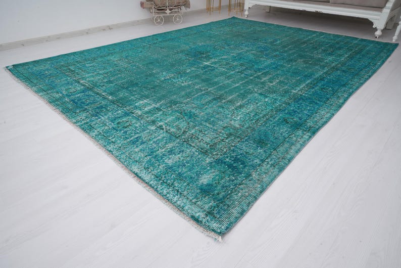 May include: A teal blue vintage rug with a distressed, faded look. The rug has a subtle pattern and is made of a soft, woven material.