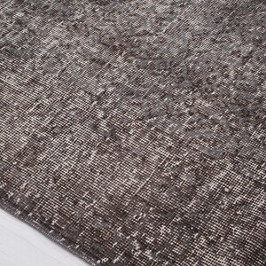 May include: A close-up of a dark gray rug with a subtle pattern. The rug has a distressed, vintage look and is made of a soft, woven material.