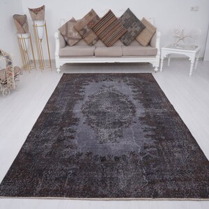 May include: A dark gray vintage rug with a faded floral pattern. The rug has a distressed look and is perfect for adding a touch of bohemian style to any room.