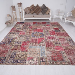 K&ouml;nnte beinhalten: Ein gro&szlig;er, mehrfarbiger Patchwork-Teppich mit einem abgenutzten, Vintage-Look. Der Teppich besteht aus verschiedenen Quadraten und Rechtecken in unterschiedlichen Farben und Mustern, darunter Rot, Blau und Creme. Der Teppich liegt auf einem wei&szlig;en Boden in einem Raum mit wei&szlig;en W&auml;nden.