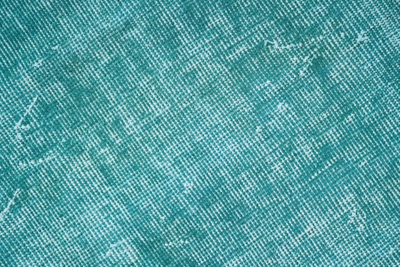 May include: A close-up of a teal blue textured fabric with a subtle grid pattern.