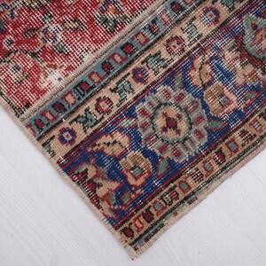 K&ouml;nnte beinhalten: Nahaufnahme eines Teppichs mit einem roten, blauen und beigen Muster. Der Teppich hat einen Fransenrand und komplizierte Designs.