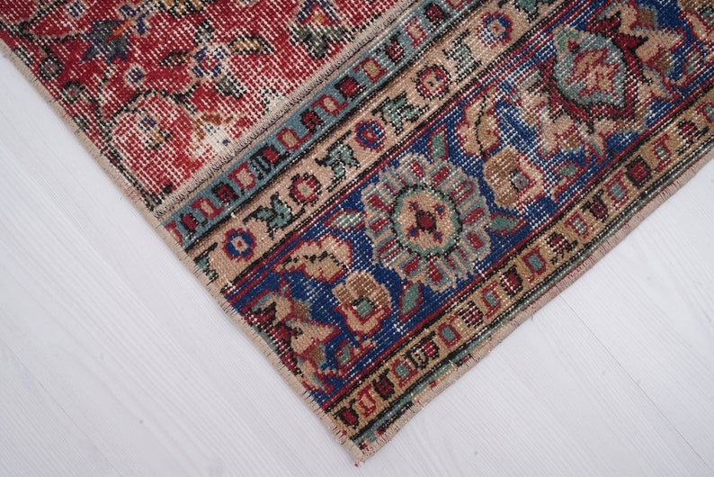K&ouml;nnte beinhalten: Nahaufnahme eines Teppichs mit einem roten, blauen und beigen Muster. Der Teppich hat einen Fransenrand und komplizierte Designs.