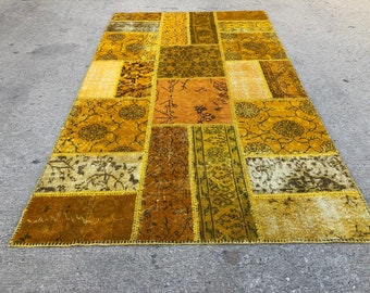 May include: A patchwork rug with a yellow and brown color scheme. The rug is made of different pieces of fabric sewn together, creating a unique and interesting design.